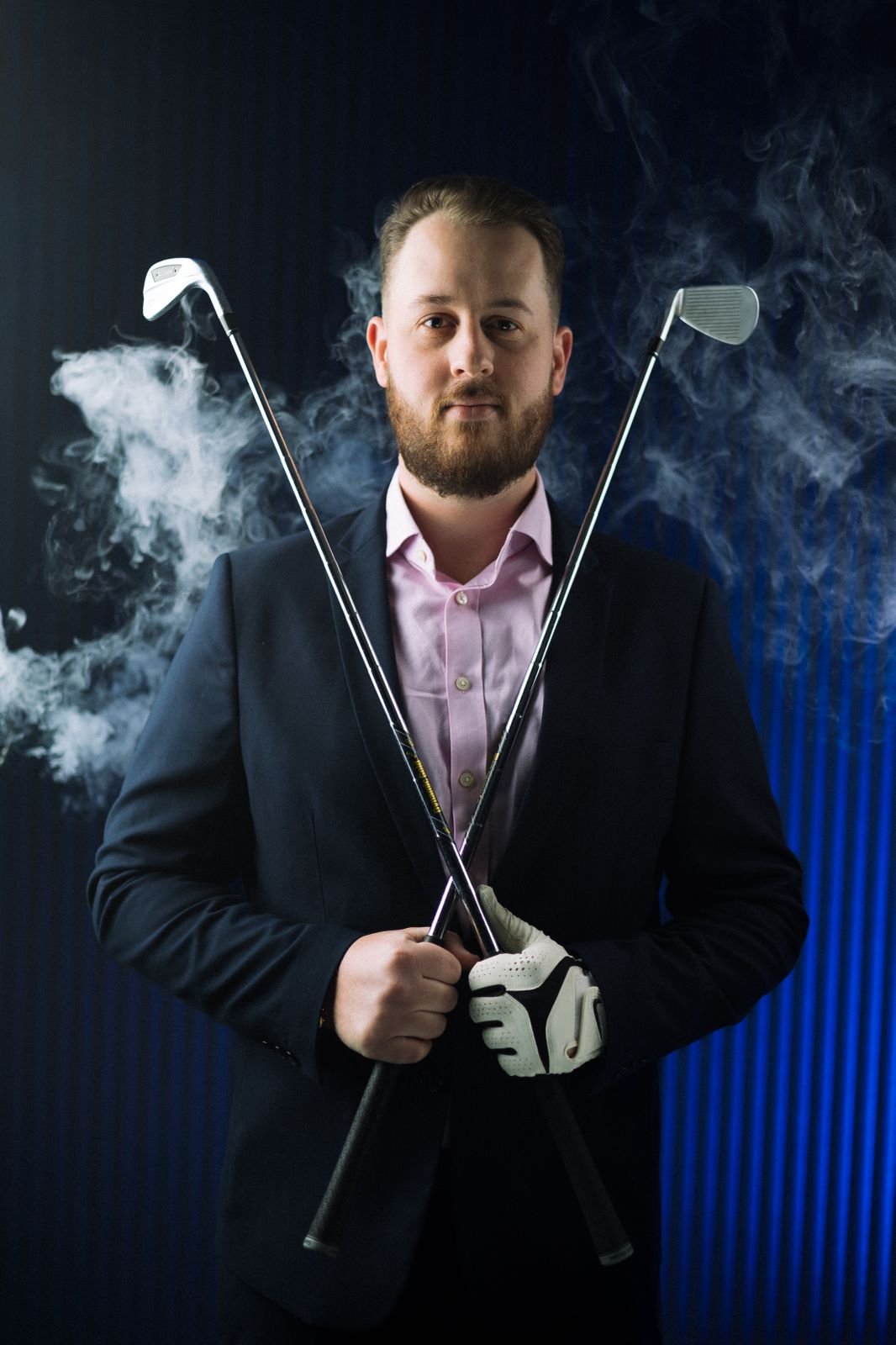 Samuel Longfield of Understand Your Group holding two golf clubs in a cross pattern across his chest.