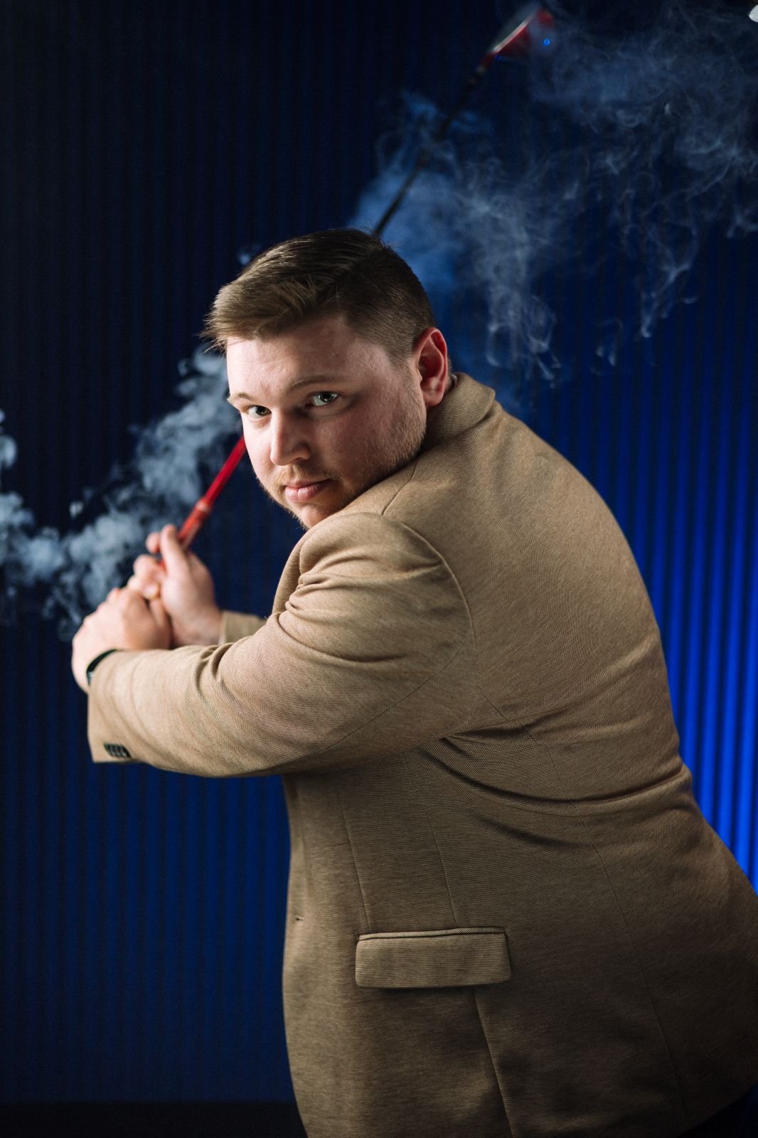 Michael Brimson from Understand Your Group swinging a golf club in a suit with smoke in the background.